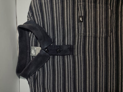 Close-up of a black and white striped shirt with a pocket and strap detail.