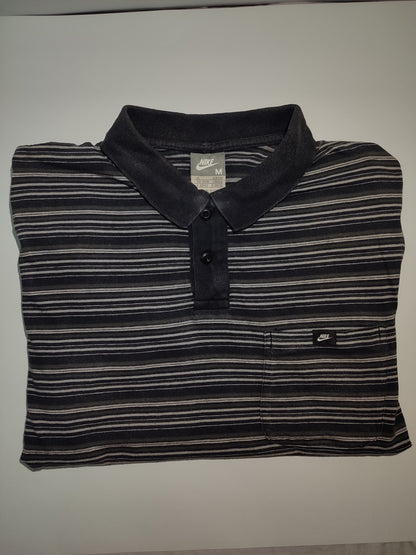 Folded black and gray striped polo shirt with Nike logo on a white background